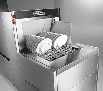 HOBART FLOW Line dishwashing system with plates on the conveyor and a separate tray lane in the background