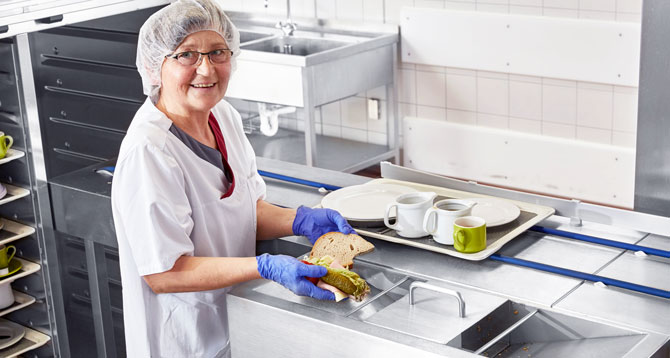 Close-up of the FLOW Line featuring integrated food waste disposal technology for hygienic removal of leftovers and automated conveyor system for trays and dishes in commercial kitchens.