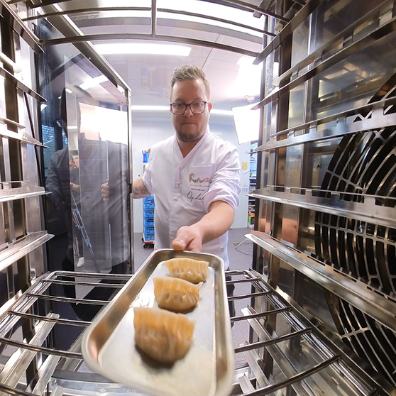 Tray with prepared food being placed into the cooking chamber of a HOBART CHEF’S COMBI, viewed from inside the appliance for a dynamic perspective on the loading process.