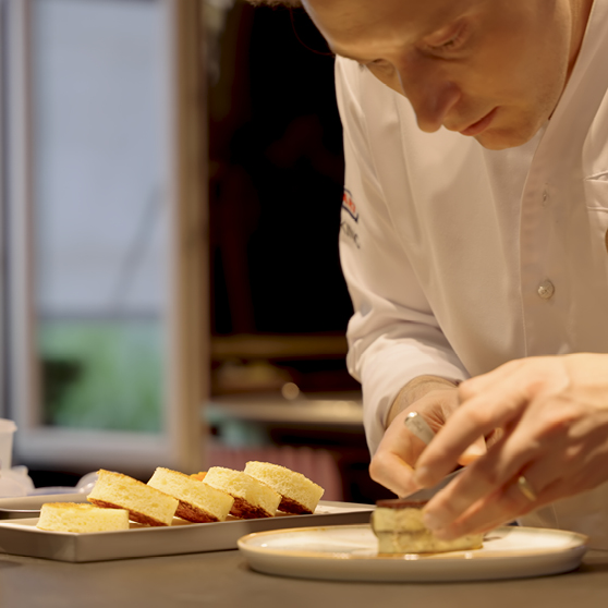 Chef arranging finely prepared dishes on plates at a kitchen pass, organizing components with precision as part of the plating process.