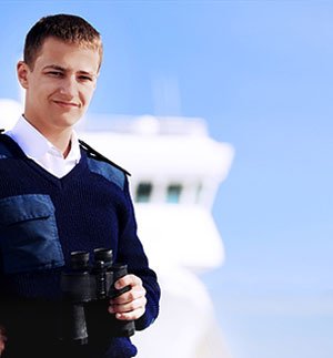 Person in a dark blue uniform holding binoculars with a large ship visible in the background.