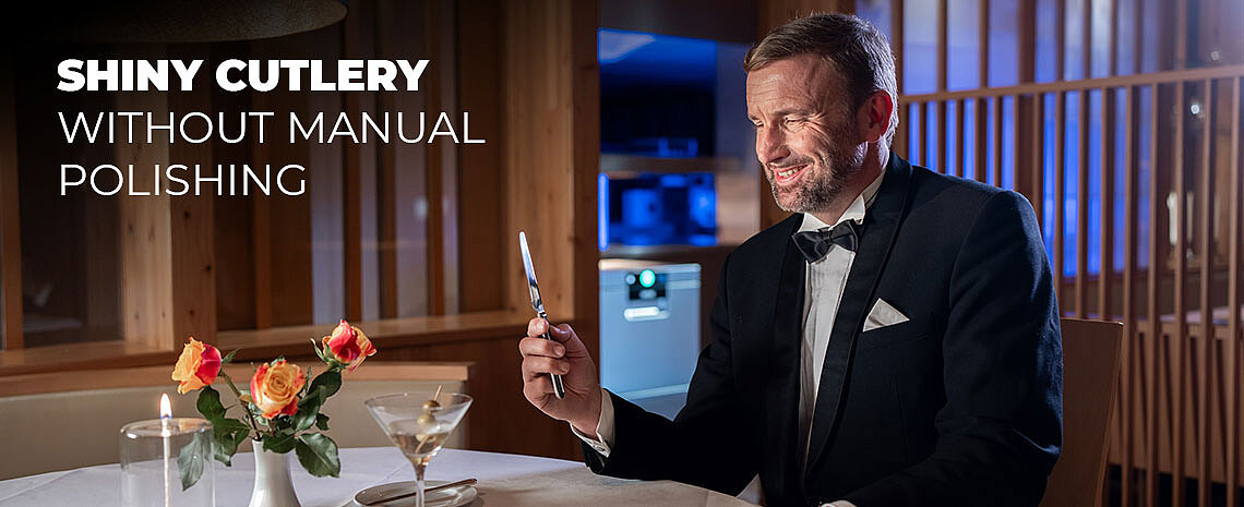 A man holds a shiny knife at a set table, with a HOBART undercounter dishwasher visible in the background