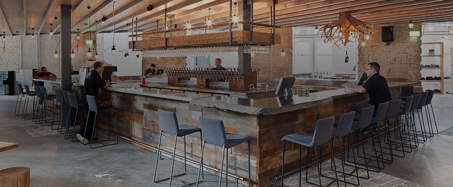 Spacious bar area inside Stone Brewing Berlin featuring a large central counter, wooden elements, high seating, and an open industrial design that complements the brewery atmosphere.