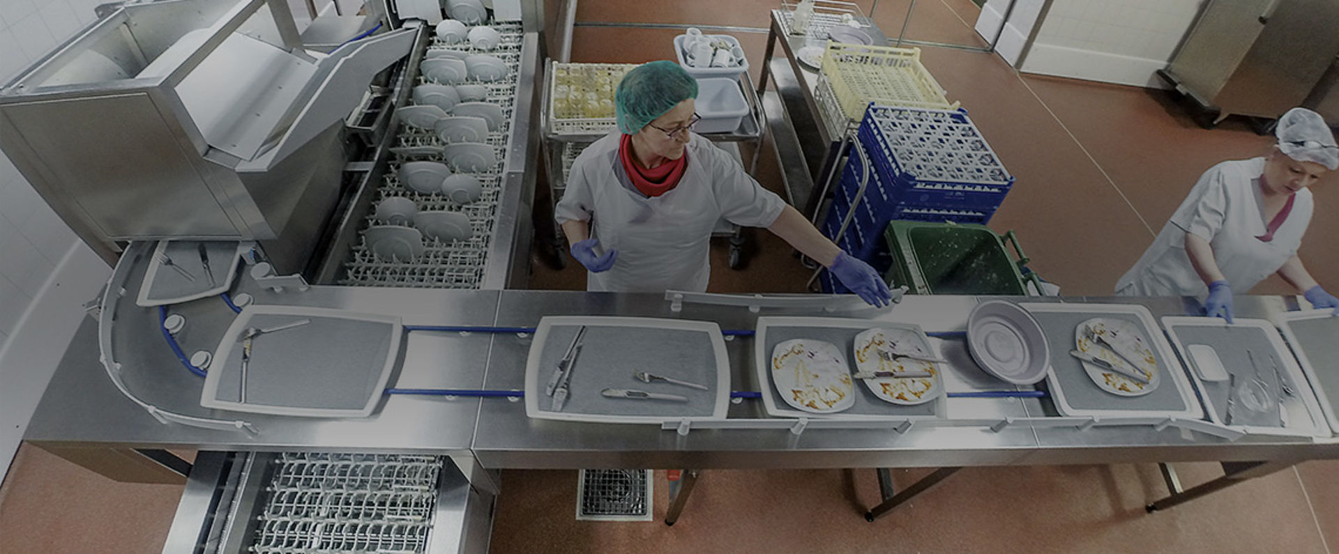 Overhead view of the dishwashing area in the SHG Clinic Völklingen, where staff members sort trays, plates, and cutlery onto the HOBART AutoLINE conveyor system that automates the loading process.