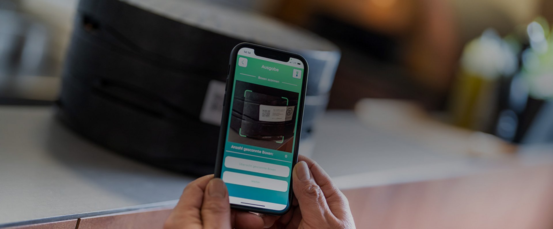 A smartphone displays the rezzeat app interface used for managing reusable pizza box distribution and return, shown in front of stacked boxes on a counter.
