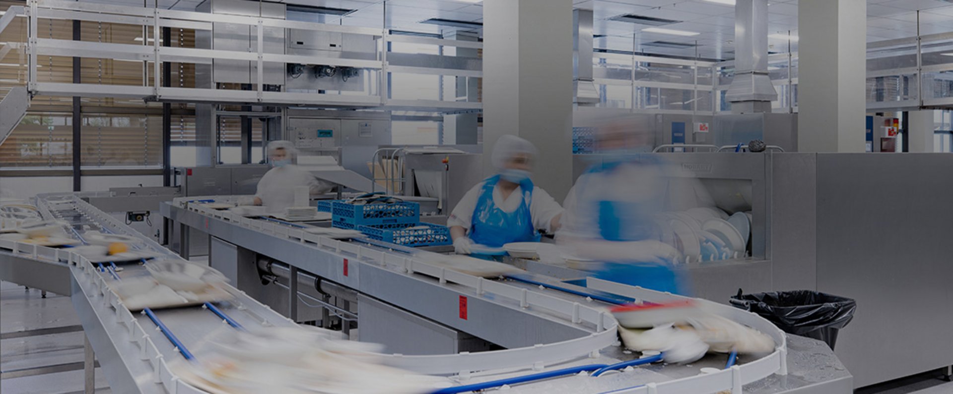 In the dishwashing area of the University Hospital Mannheim, multiple HOBART FTNi conveyor dishwashers and a long cart washing system operate continuously to clean large volumes of trays and kitchen equipment, showcasing an efficient and hygiene‑focused setup designed for high‑capacity food service operations.