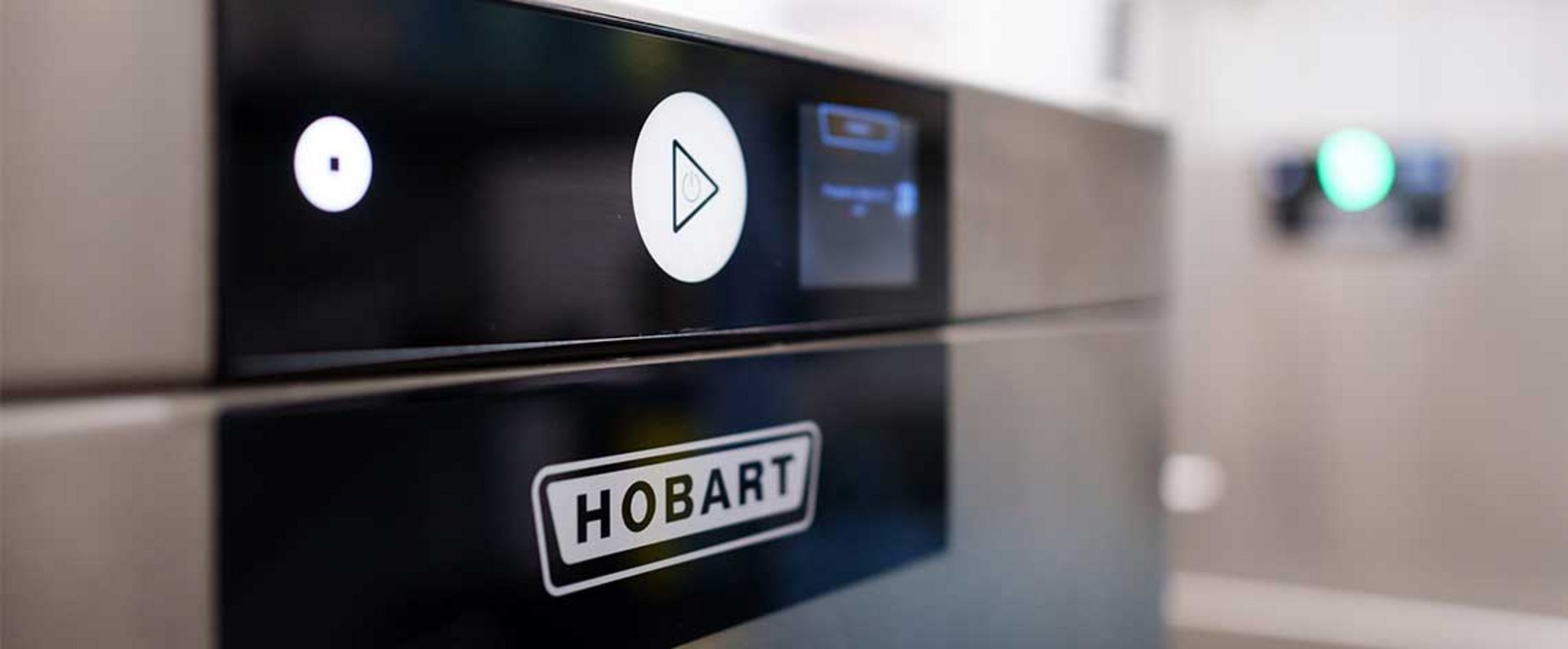 Close‑up view of the control panel of a HOBART dishwasher, showing the logo, stainless‑steel surface and illuminated touch buttons.