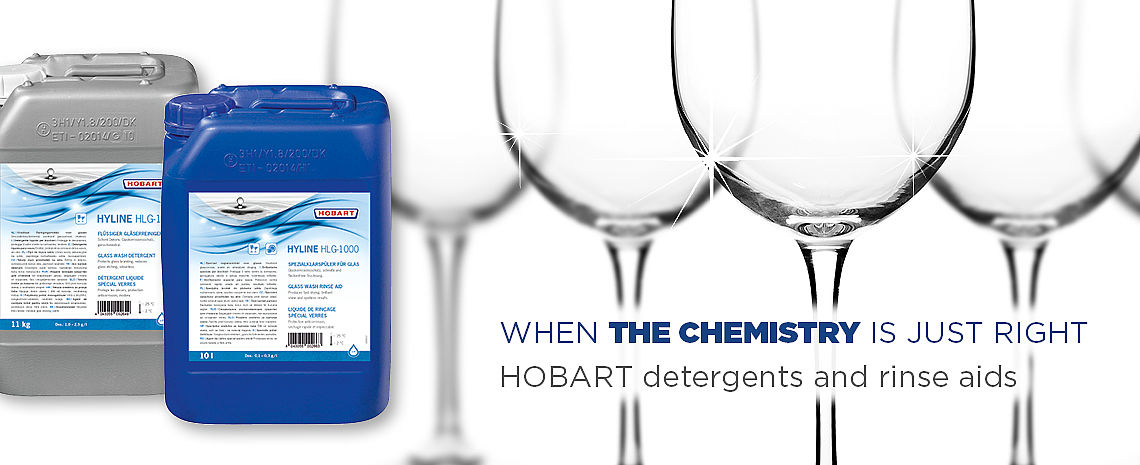Two large HOBART HYLINE detergent and rinse aid containers placed next to a row of clear wine glasses with bright reflections, accompanied by the text “WHEN THE CHEMISTRY IS JUST RIGHT – HOBART detergents and rinse aids” on a light background.
