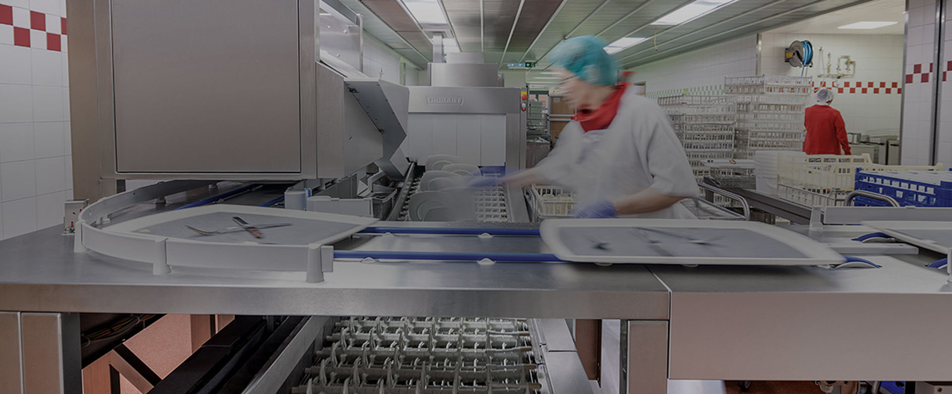Tray transport section of the HOBART AutoLINE in the SHG Clinic Völklingen showing trays moving along the curved conveyor track toward the automated washing zone.