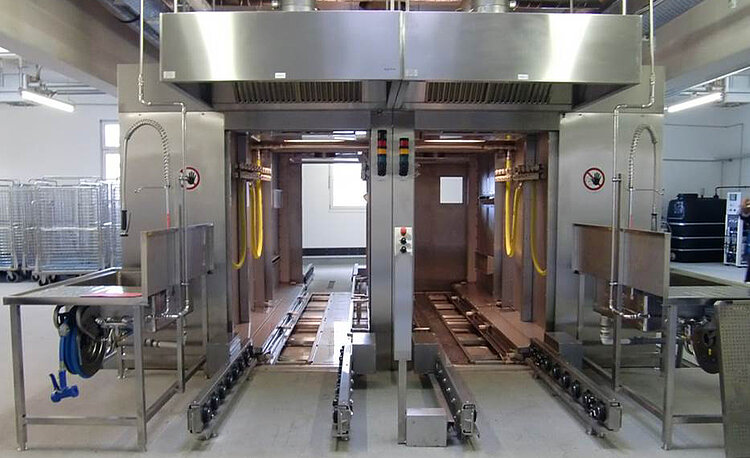 HOBART stainless steel industrial washing system featuring two large washing chambers, yellow hose lines, and automated cleaning technology, designed for disinfecting carts, pallets, and containers in food and pharmaceutical industries.