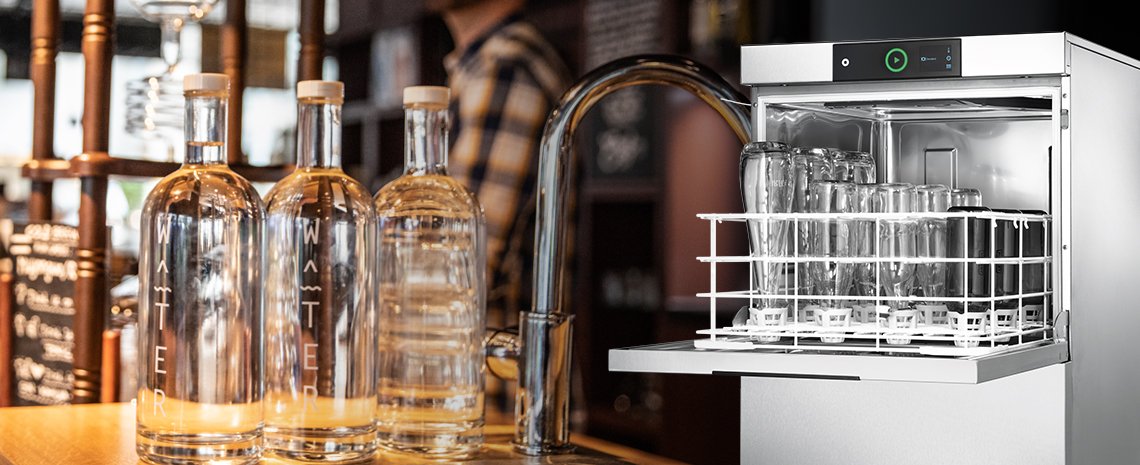 Professional dishwasher for glass bottles in use at a bar, featuring an open rack with bottles and additional water bottles on the counter – perfect for hospitality and hygienic cleaning.